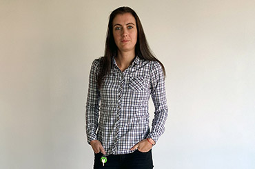 Telerik Academy graduate in shirt with square pattern in front of a white wall at Tick42's office
