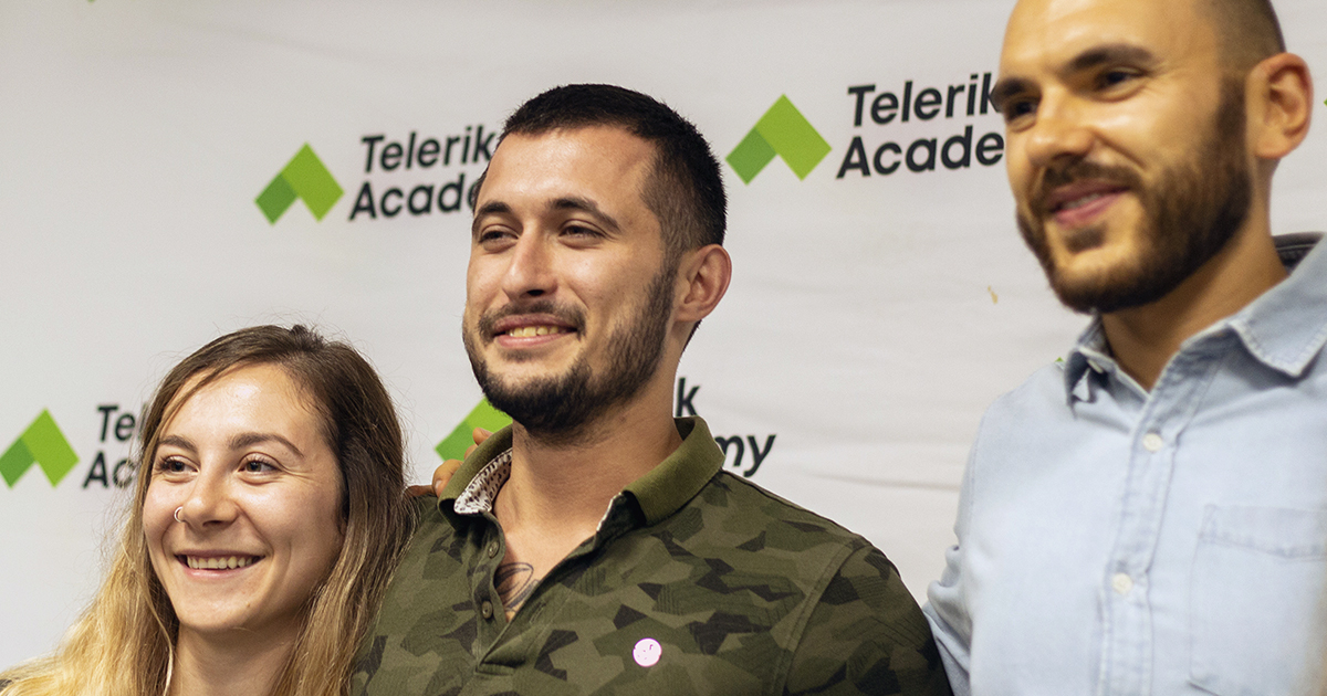 Photo of Daniel and two of his trainers during his graduation in front of a wall with telerik academy's logo on it 